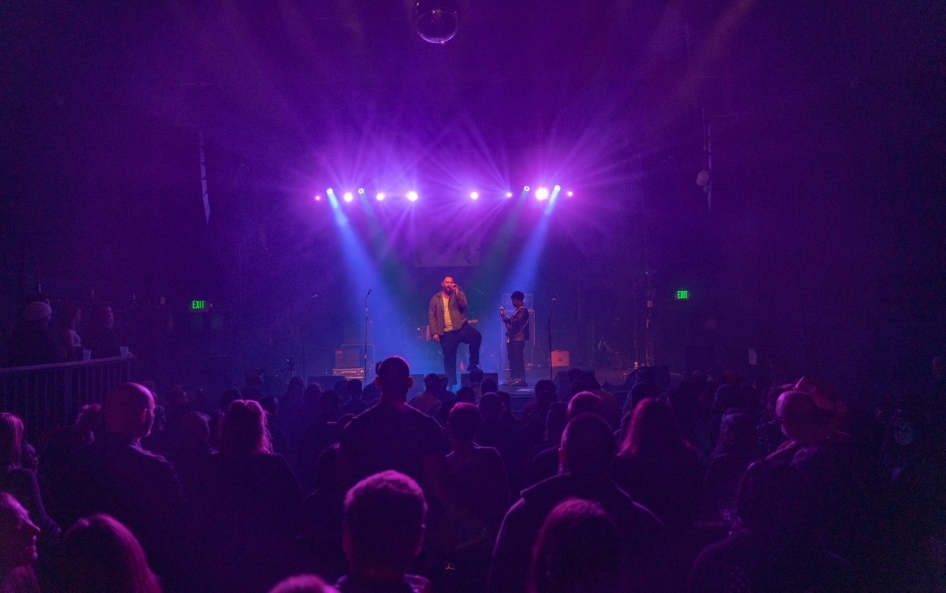 Audience watching a live band bathed in purple light.